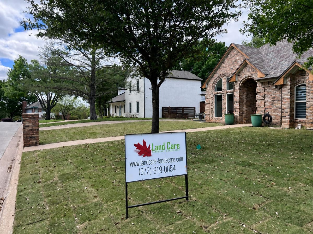 Fall cleanup on a residential lawn with a Land Care yard sign