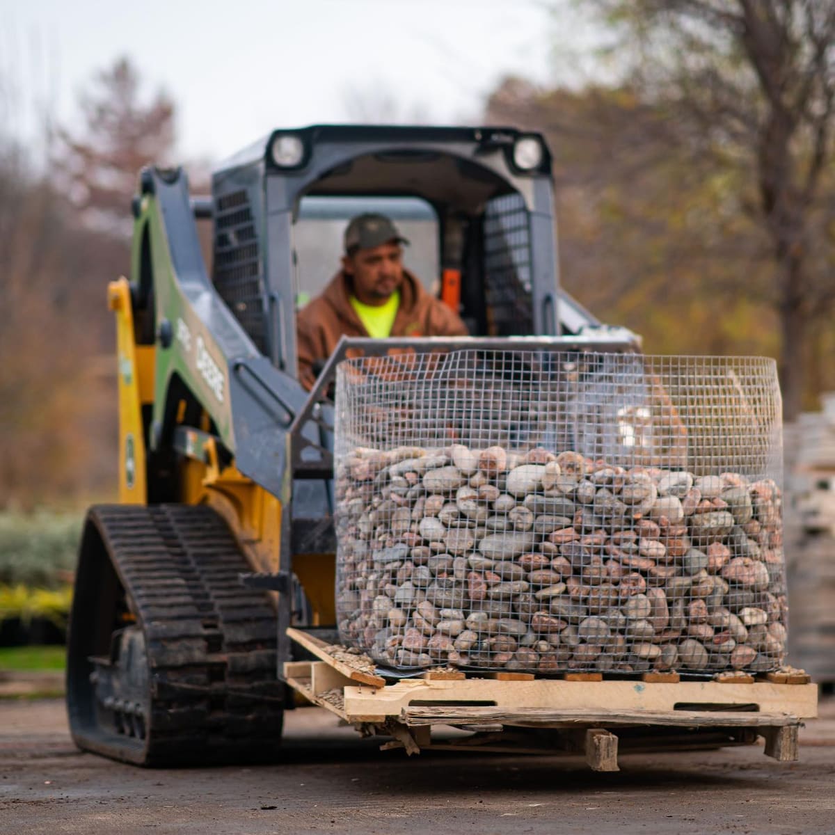 Skid steer delivering river rock