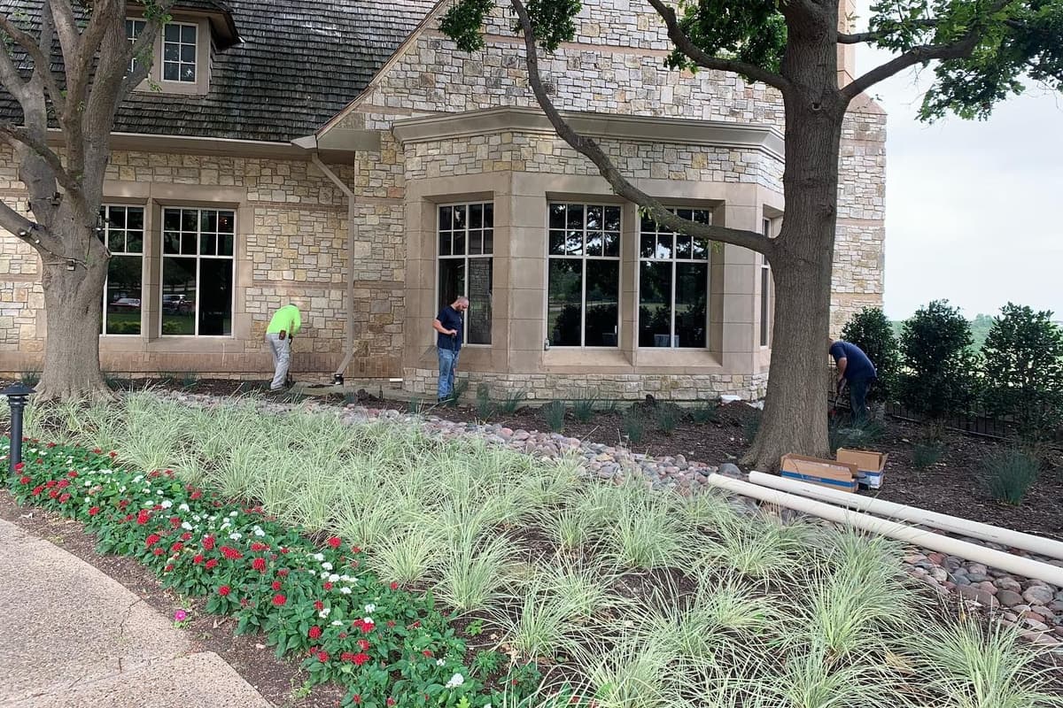 Clean river rock bed with steel edging along a modern commercial building foundation