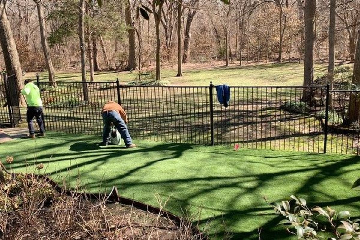 Fresh rolls of sod being laid in staggered rows across graded soil on a large property
