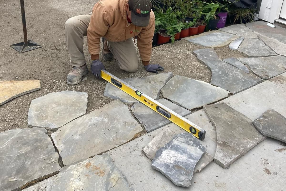 Mason setting natural stone on a new patio with string lines and levels